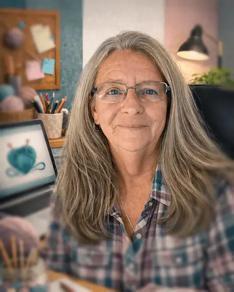 Portrait of Nancy Smyth, The YarnyBookkeeper, smiling in a cozy home office with yarn and a laptop.